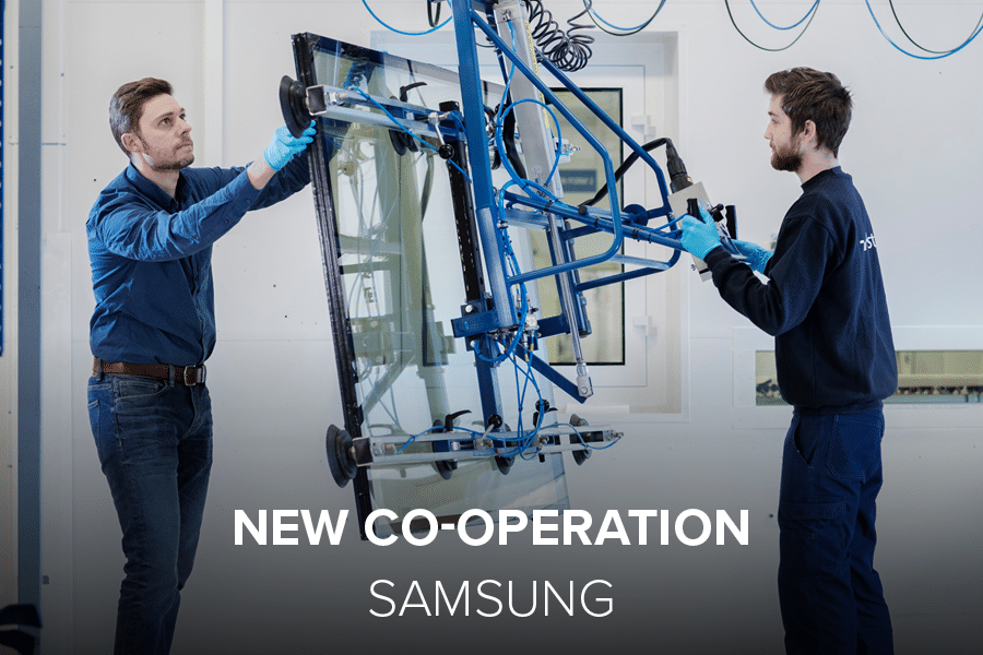 Two men working on dynamic glass in the factory. White text says "New Co-operation".