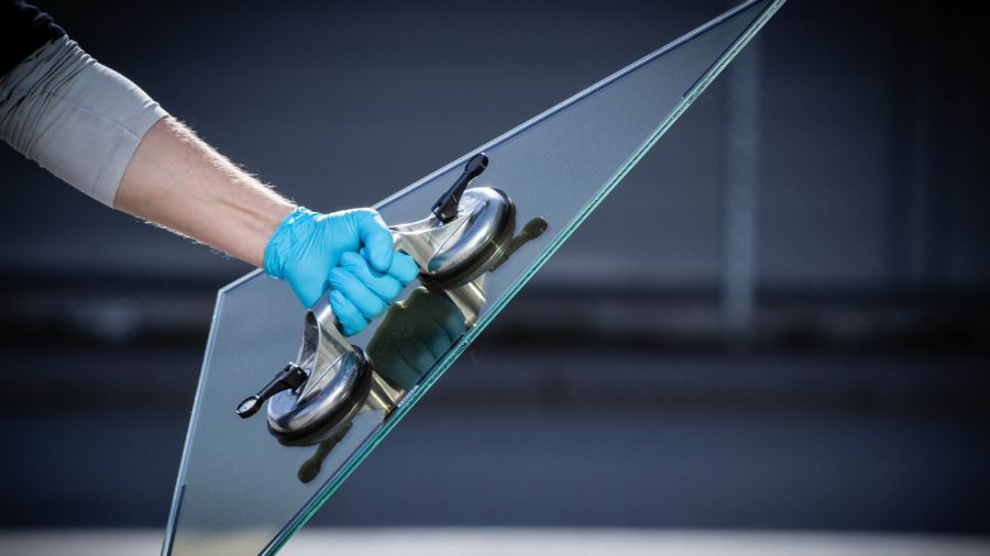 Hand in a blue glove holding a triangle of glass