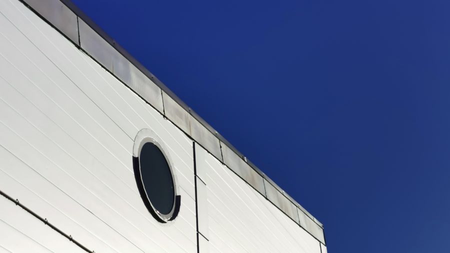 A round facade glass on a white building, blue sky in the background