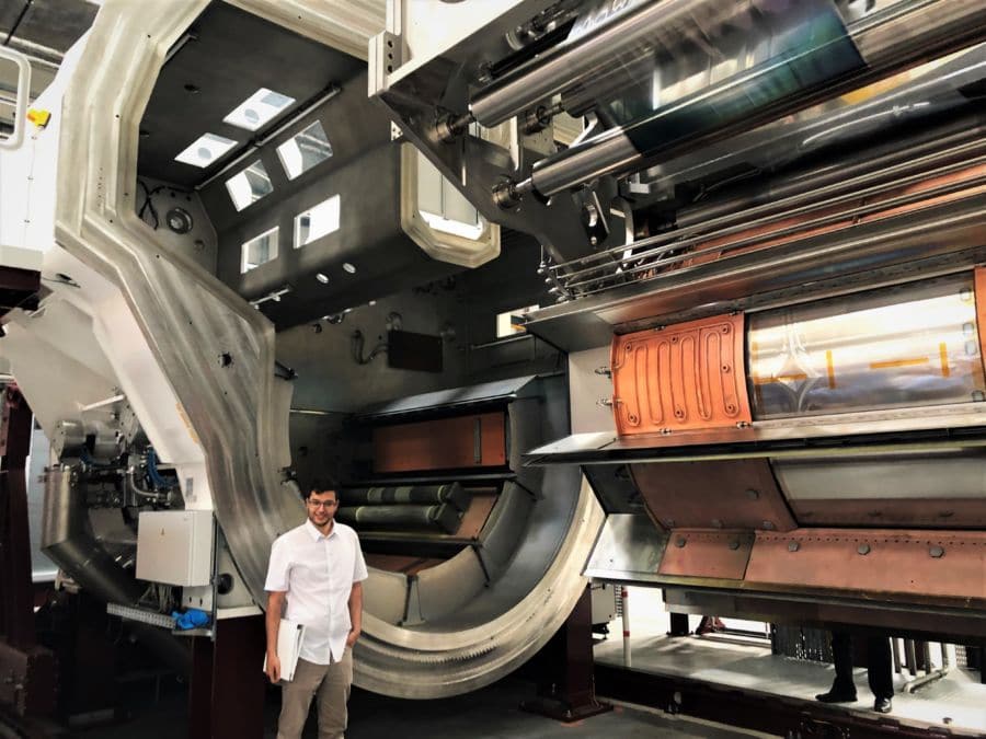 A man standing infront of a huge sputter machine.